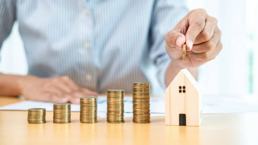 Business woman holding coin to putting into house piggy bank with increasing coins stack for saving